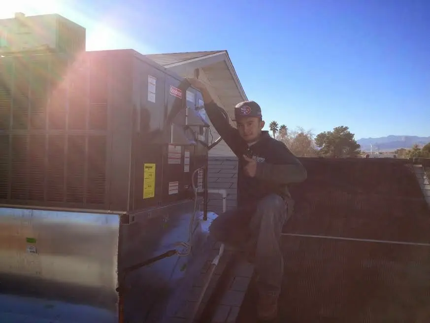 HVAC technician performing AC Tune-Up on a rooftop unit in Vinton